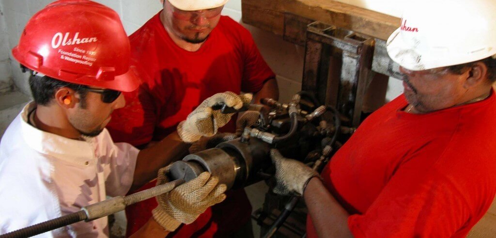 technicians performing wall repair on basement